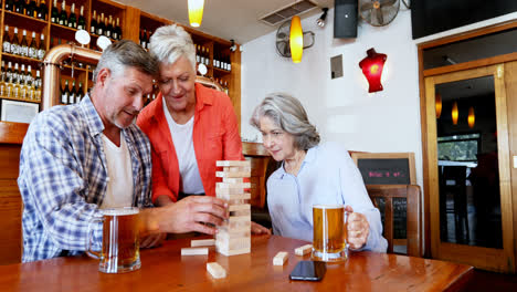 Ältere-Freunde-Toasten-Ein-Glas-Bier,-Während-Sie-Jenga-4k-Spielen
