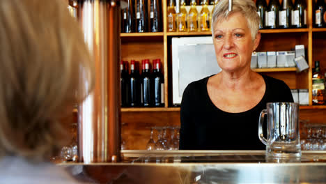 Senior-waitress-interacting-with-customer-at-counter-4k