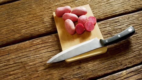 Sweet-potatoes-and-kitchen-knife-on-a-chopping-board-4k