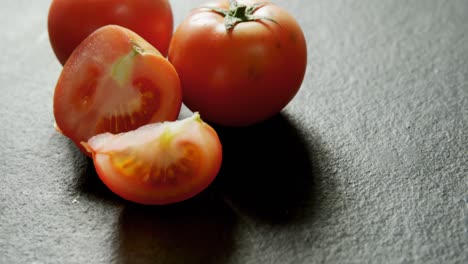 Full-and-half-tomatoes-arranged-on-grey-background-4K-4k