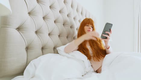 Schöne-Frau,-Die-Ihr-Mobiltelefon-Benutzt,-Während-Sie-Sich-Auf-Dem-Bett-Entspannt,-4k