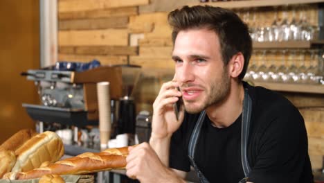 Waiter-talking-on-mobile-phone-at-counter-4k
