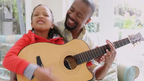 Father-and-daughter-playing-guitar-in-living-room-4k