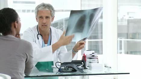 Médico-Maduro-Y-Su-Paciente-Examinando-Una-Radiografía