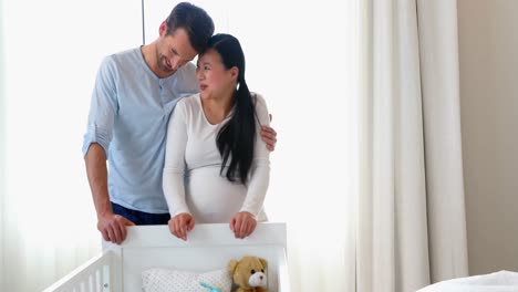 Pregnant-couple-looking-at-baby-cot-in-bedroom-4k