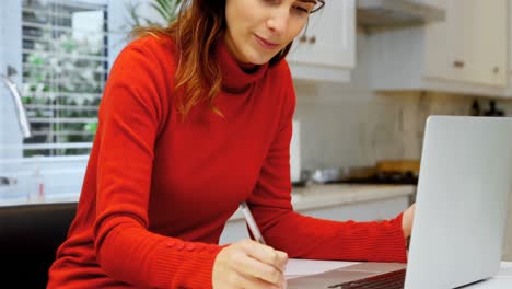Woman-using-laptop-in-kitchen-4k