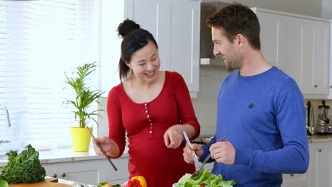 Couple-using-digital-tablet-while-preparing-salad-in-kitchen-4k