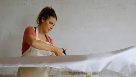 Woman-cutting-fabric-for-surfboard-4k
