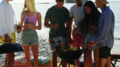 Friends-cooking-food-on-barbecue-and-drinking-beer-at-the-beach-4k