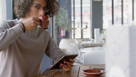 Man-having-coffee-while-using-tablet-4k
