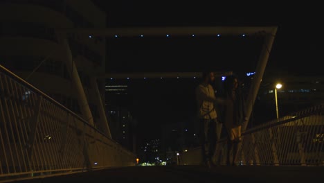 Couple-walking-together-hand-in-hand-on-a-bridge-4k