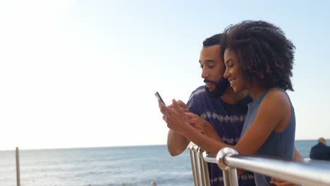 Couple-using-mobile-phone-in-the-beach-4k