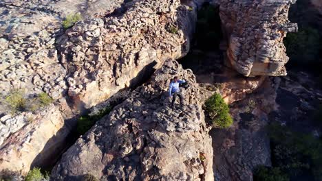 Male-rock-climber-standing-over-a-rocky-mountain-4k