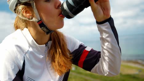 Ciclista-Femenina-Bebiendo-Agua-En-Un-Camino-Rural-4k