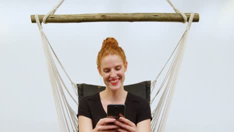 Businesswoman-using-mobile-phone-while-relaxing-on-a-hammock-4k