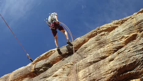 Mountaineer-rappelling-down-the-hill-with-the-help-of-rope--4k-