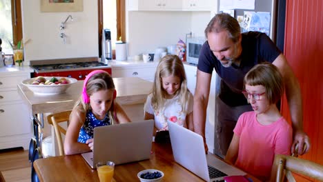 Father-and-daughters-using-laptop-in-kitchen-4k