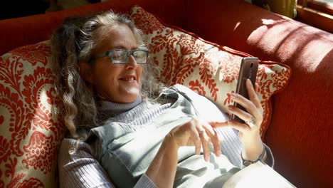 Mature-woman-using-mobile-phone-in-living-room-4k