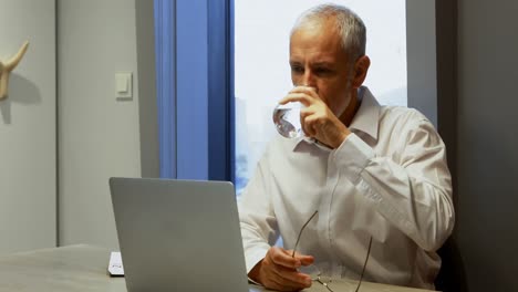Geschäftsmann-Trinkt-Ein-Glas-Wasser,-Während-Er-Einen-4K-Laptop-Benutzt