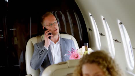 Businessman-talking-on-mobile-phone-while-travelling-in-private-jet-4k