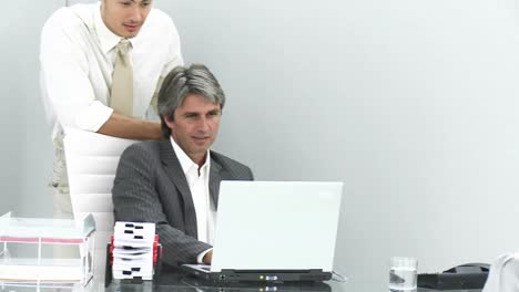 Two-friendly-businessmen-looking-at-a-laptop
