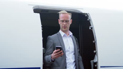 Businessman-talking-on-mobile-phone-while-moving-out-from-private-jet-4k