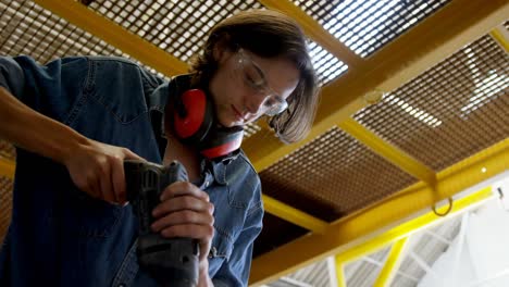 Female-welder-using-drill-machine-in-workshop-4k