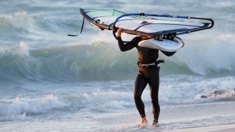 Surfista-Masculino-Llevando-Windsurfista-En-La-Playa-4k