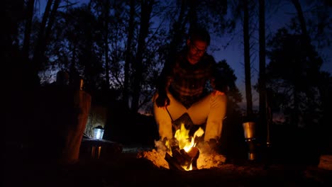 Man-sitting-near-campfire-in-the-forest-4k