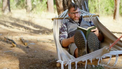 Man-reading-a-book-while-relaxing-in-a-hammock-4k