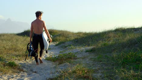 Männlicher-Surfer,-Der-Mit-Surfbrett-Am-Strand-Spaziert-4k