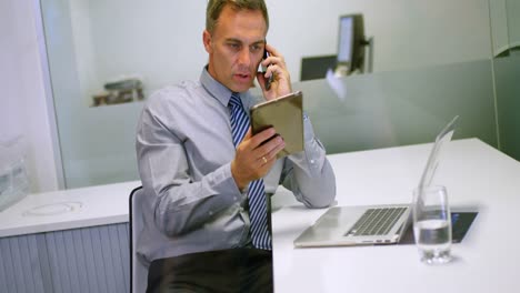 Geschäftsmann-Nutzt-Digitales-Tablet,-Während-Er-Mit-Dem-Mobiltelefon-4k-Spricht