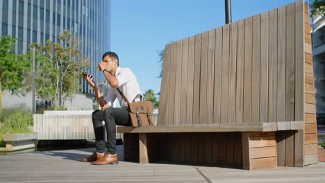 Man-sitting-on-bench-and-talking-on-mobile-phone-4k