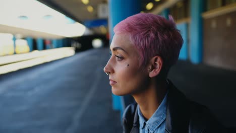 Pink-hair-woman-waiting-for-train-in-railway-station-4k