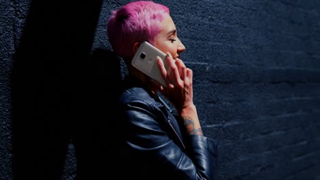 Pink-hair-woman-talking-on-mobile-phone-in-alley-4k
