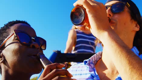 Gruppe-Von-Freunden,-Die-Am-Strand-Bierflaschen-Anstoßen-4K