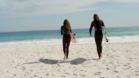 Couple-walking-with-surfboard-on-the-beach-4k