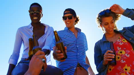 Gruppe-Von-Freunden,-Die-Am-Strand-Bierflaschen-Anstoßen-4K