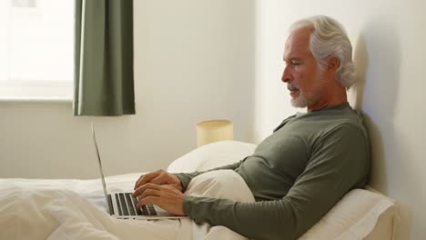 Senior-man-using-laptop-on-bed-in-bedroom-4k