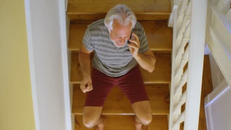 Senior-man-talking-on-mobile-phone-on-stair-at-home-4k