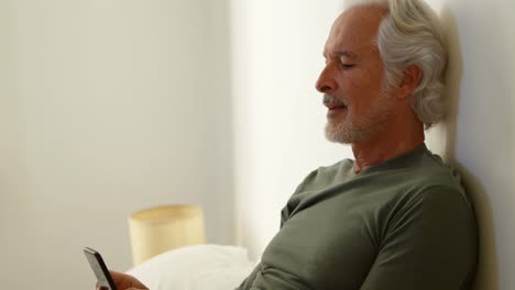 Senior-man-using-mobile-phone-in-bedroom-at-home-4k