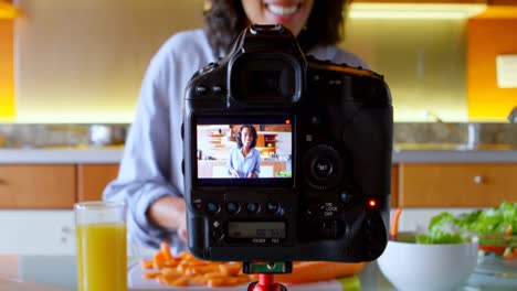Female-blogger-recording-video-while-cutting-slice-of-carrot-in-kitchen-4k