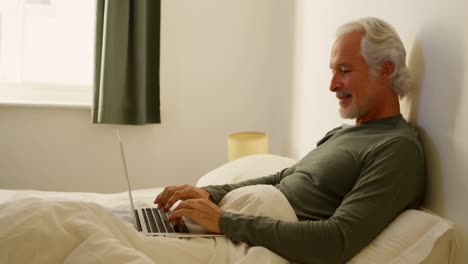 Senior-man-using-laptop-on-bed-in-bedroom-4k