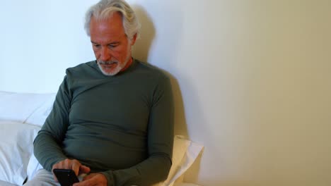 Senior-man-using-mobile-phone-on-bed-in-bedroom-4k