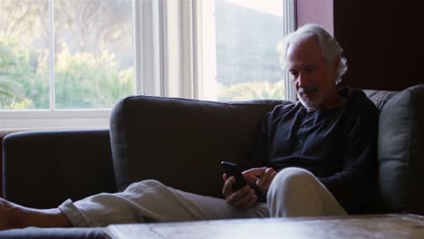 Senior-man-using-mobile-phone-on-sofa-4k