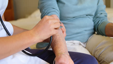 Doctor-checking-senior-woman-pulse-using-stethoscope-on-bed-at-home-4k