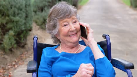 Senior-woman-talking-on-mobile-phone-on-wheelchair-4k