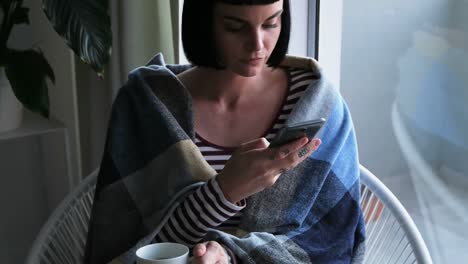 Woman-wrapped-in-blanket-using-mobile-phone-4k