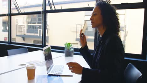 Businesswoman-talking-on-mobile-phone-while-using-laptop-4k