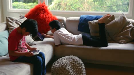 Siblings-using-digital-tablet-in-living-room-4k